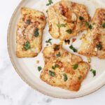 pan fried cod fillets on a plate garnished with parsley.