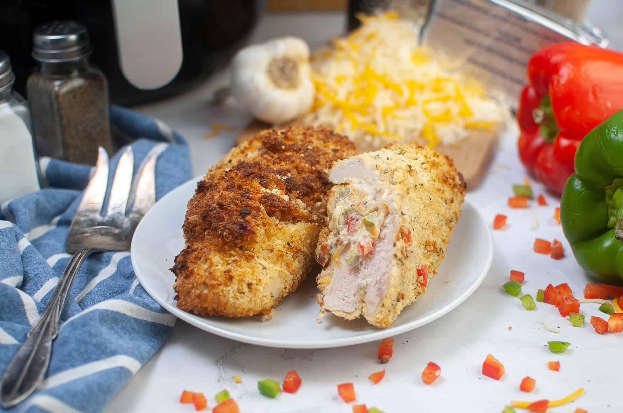 Stuffed chicken breast made in the air fryer with peppers on one side and a fork on the other side. 