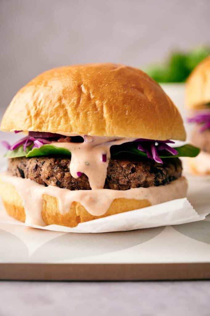 Close up of a black bean burger in a bun with relish oozing out of the sides.