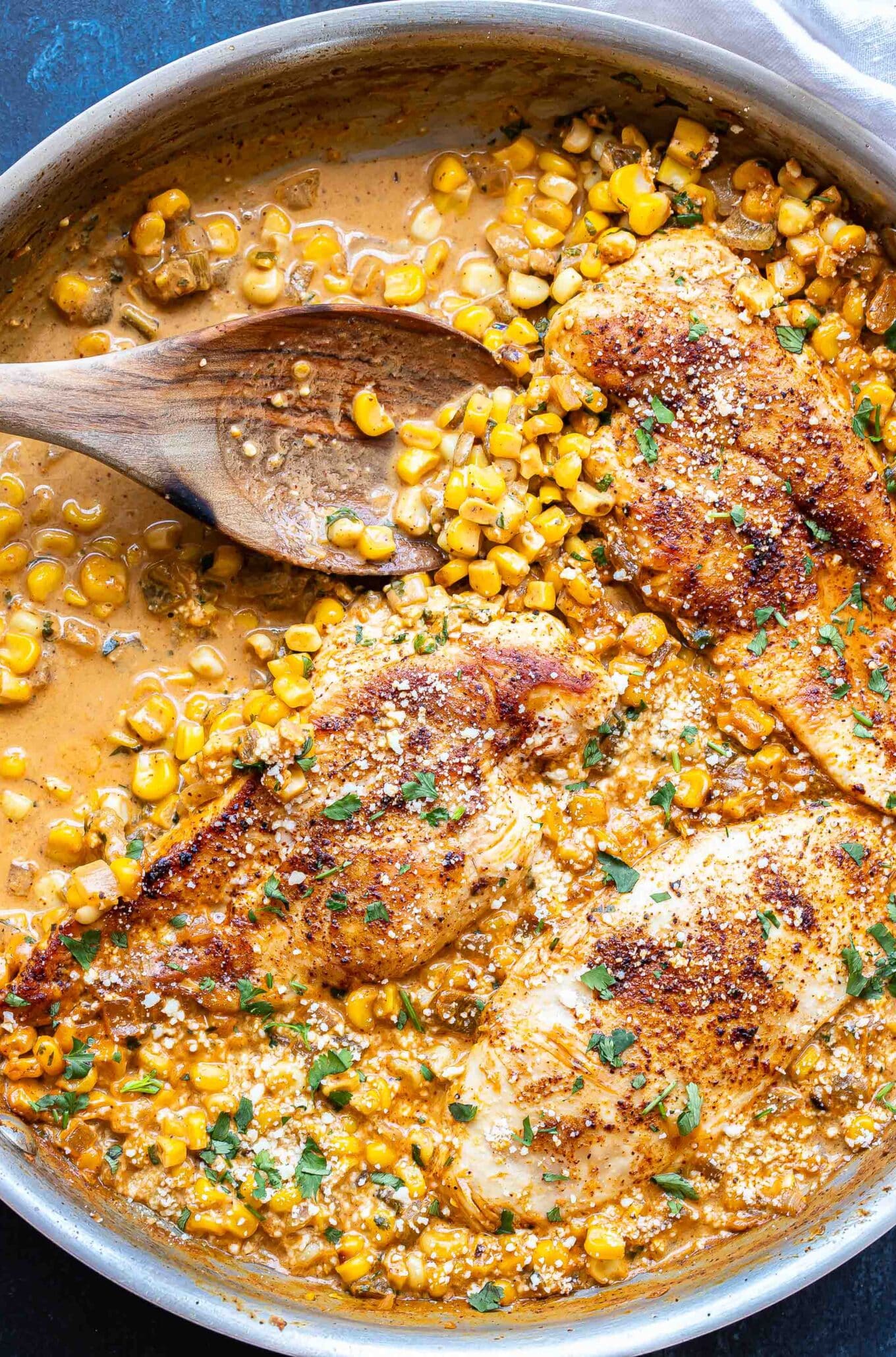 Chicken in a creamy corn sauce with a wooden spoon.