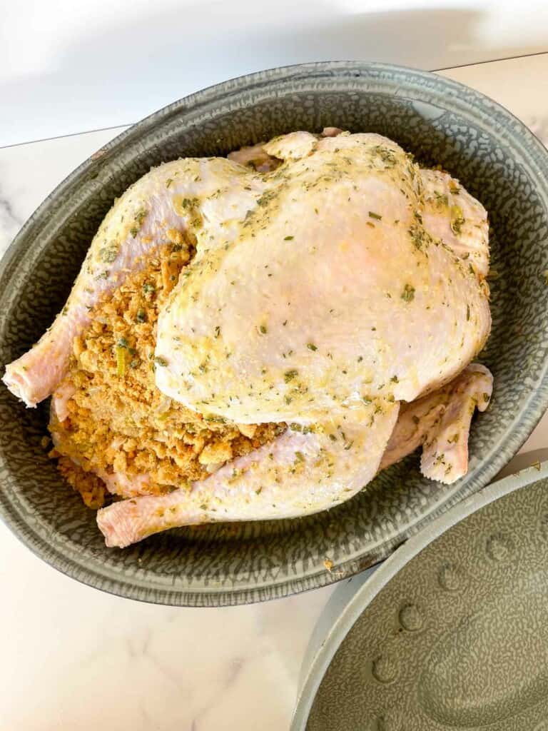 A roasted chicken in a dish next to a bowl.