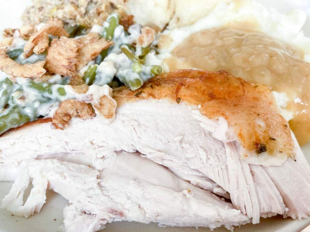 A plate of turkey, green beans and mashed potatoes.