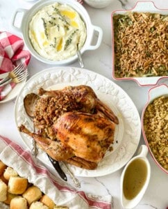 A table with a turkey, stuffing, gravy and rolls.