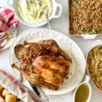 A table with a turkey, stuffing, gravy and rolls.